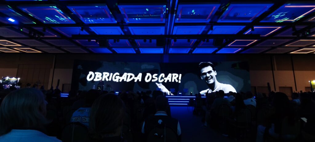 imagem de um salão iluminado em azul e ao fundo no telão a frase: Obrigada Oscar